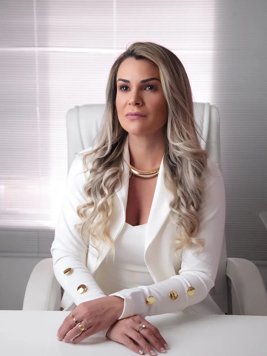 Izana Couto à mesa do escritório, de blazer branco